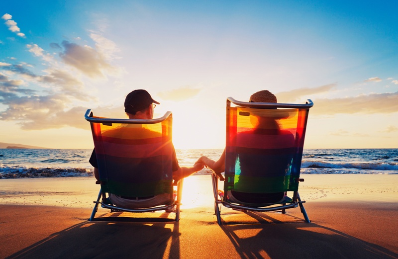 senior couple of old man and woman sitting on the beach watching sunset